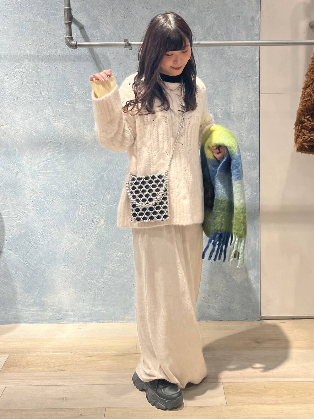 シルバー系のショルダーバッグ、ブラック系のニット/セーター、ホワイト系のスカートを着用したレディースの冬コーディネートの4枚目の写真