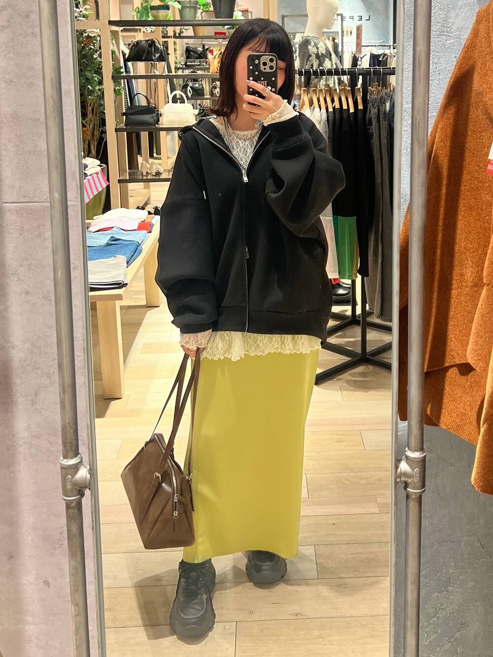 グリーン系のスカート、ブラック系のパーカー、ブラウン系のボストンバッグを着用したレディースの冬コーディネートの2枚目の写真