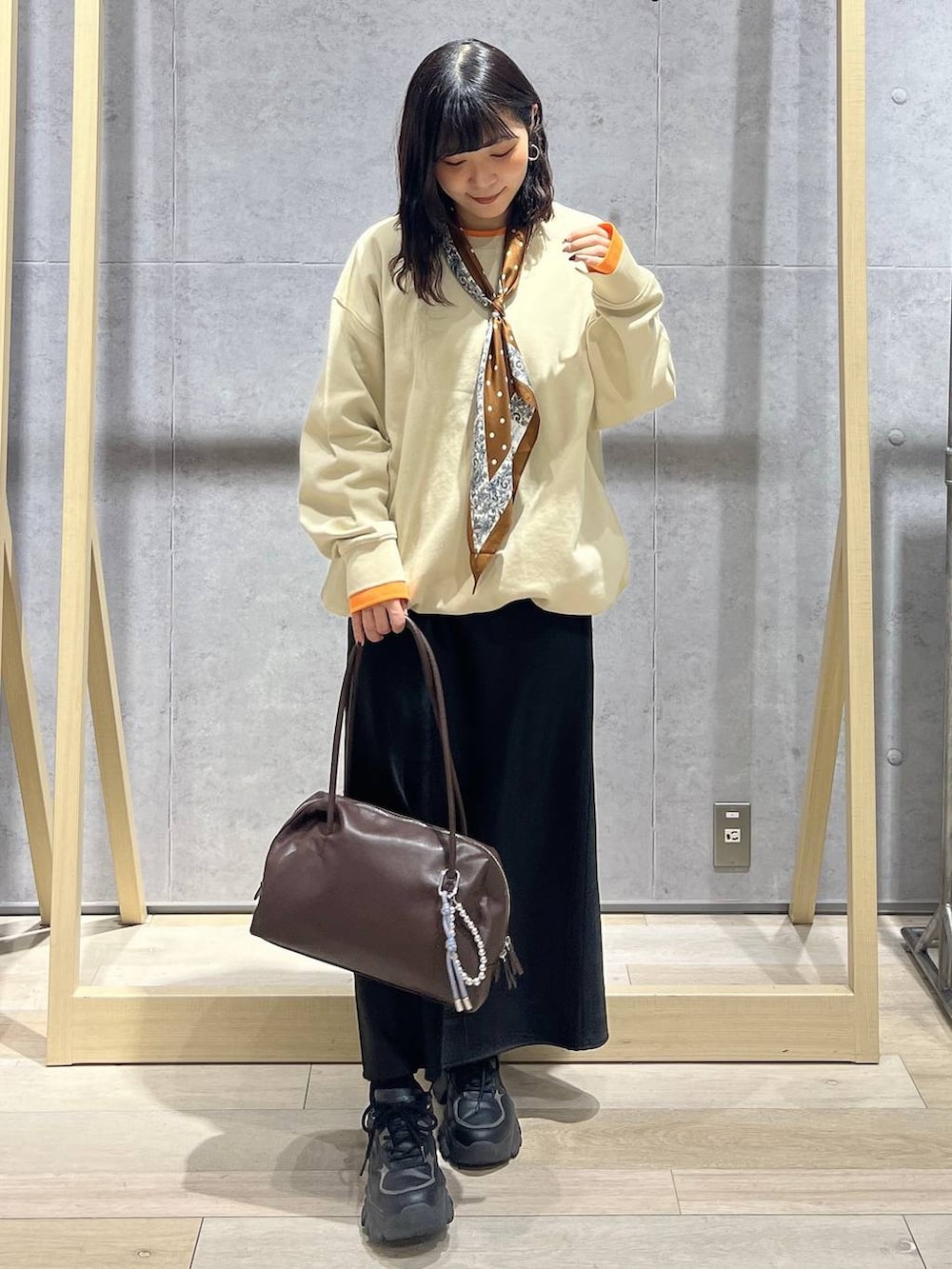 ブラック系のスカート、ブラウン系のボストンバッグ、ベージュ系のTシャツ/カットソーを着用したレディースの冬コーディネートの3枚目の写真