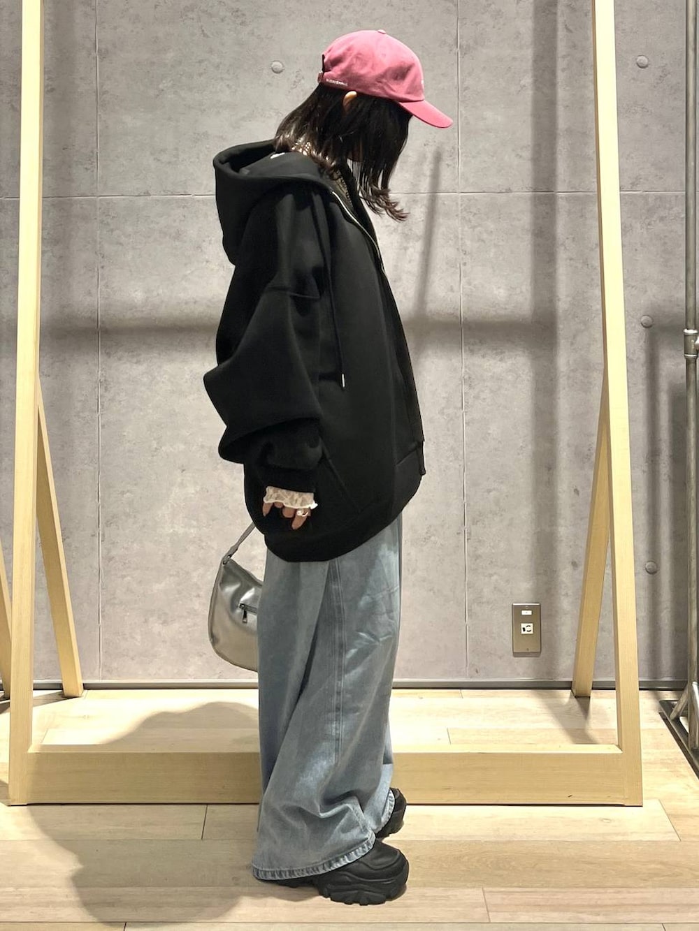 ブラック系のパーカー、ブルー系のデニムパンツ、シルバー系のショルダーバッグを着用したレディースの冬コーディネートの2枚目の写真