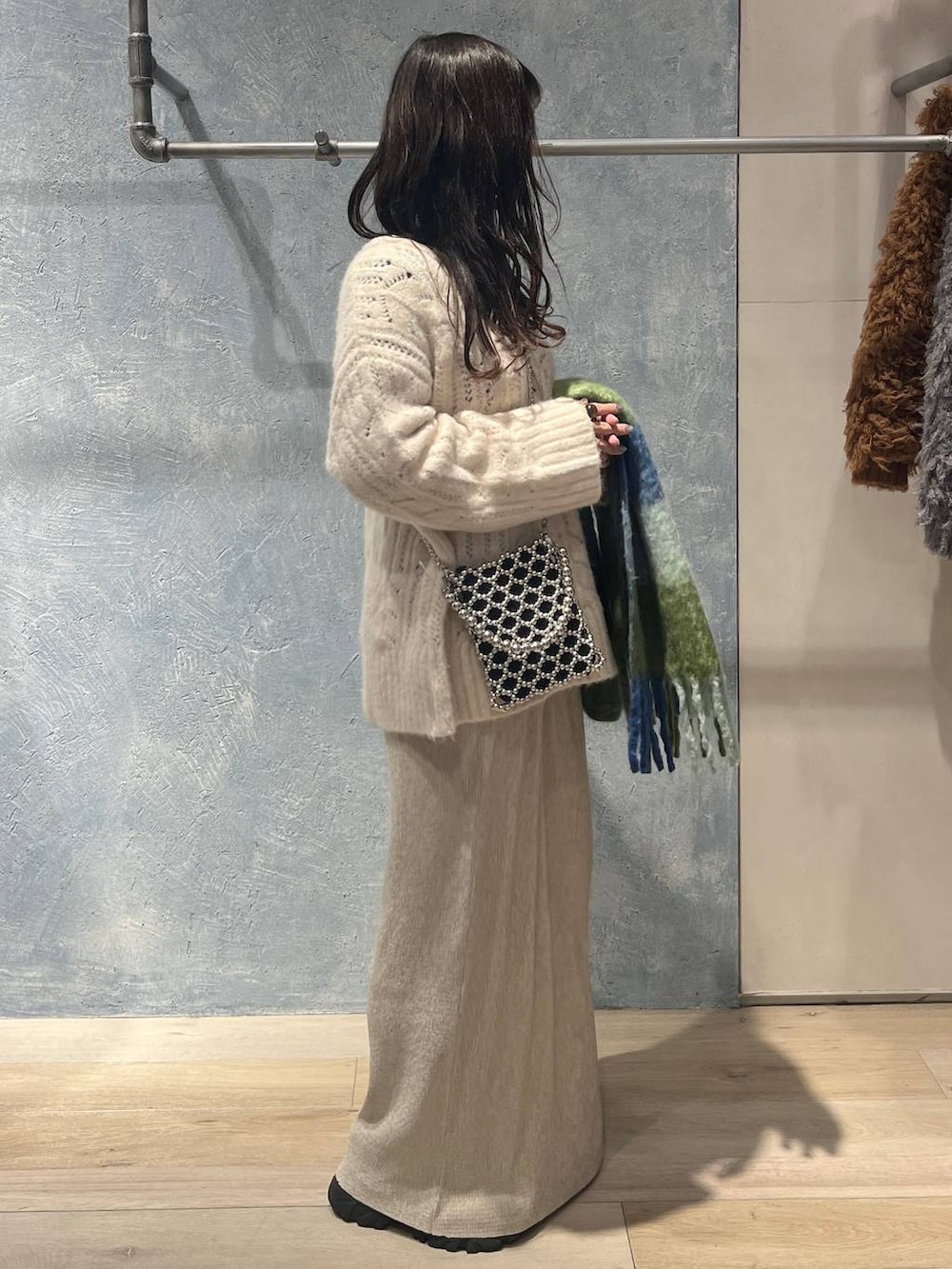 シルバー系のショルダーバッグ、ブラック系のニット/セーター、ホワイト系のスカートを着用したレディースの冬コーディネートの2枚目の写真