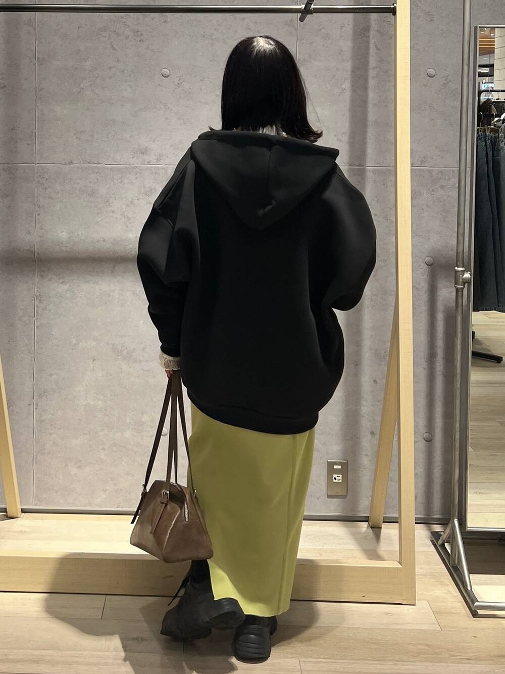 グリーン系のスカート、ブラック系のパーカー、ブラウン系のボストンバッグを着用したレディースの冬コーディネートの4枚目の写真