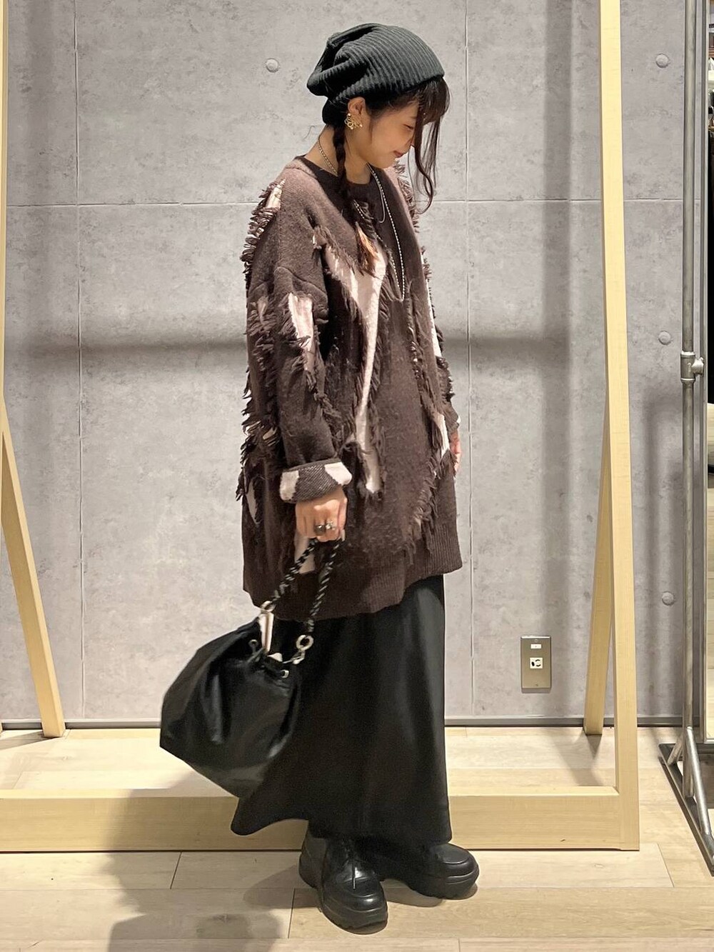 ブラック系のショルダーバッグ、ブラック系のスカート、ブラウン系のニット/セーターを着用したレディースの冬コーディネートの2枚目の写真