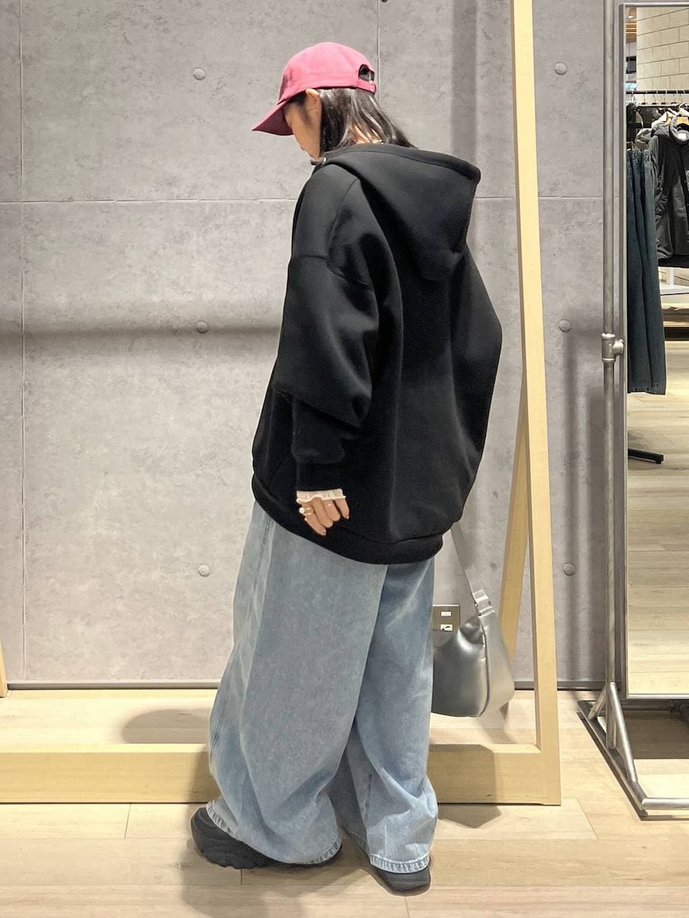 ブラック系のパーカー、ブルー系のデニムパンツ、シルバー系のショルダーバッグを着用したレディースの冬コーディネートの3枚目の写真