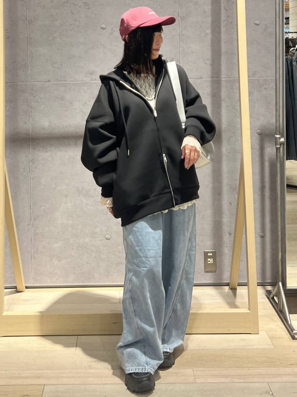 ブラック系のパーカー、ブルー系のデニムパンツ、シルバー系のショルダーバッグを着用したレディースの冬コーディネートの4枚目の写真