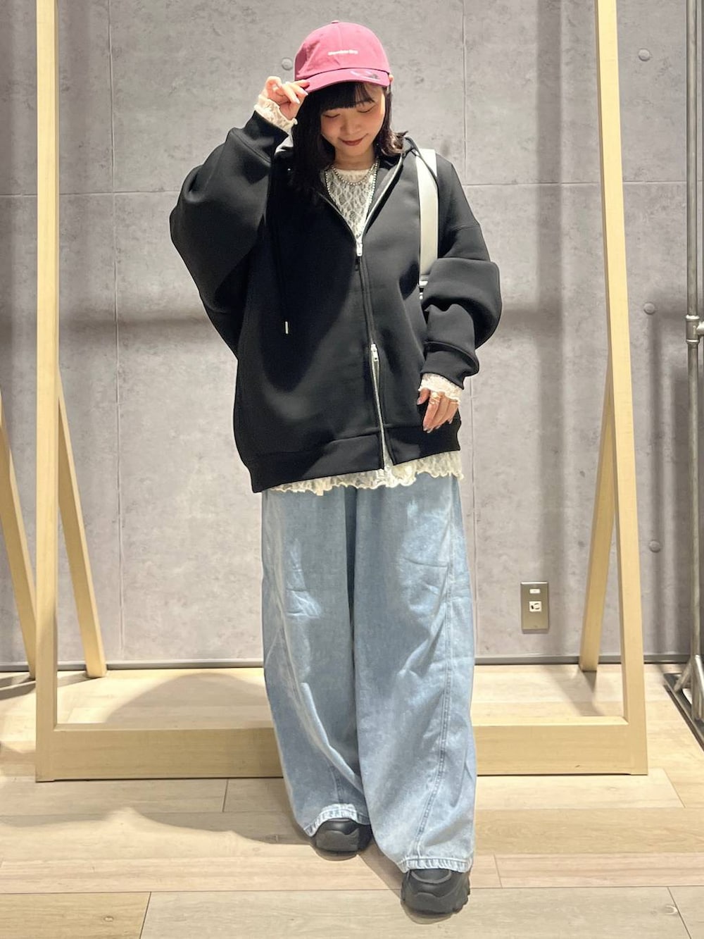 ブラック系のパーカー、ブルー系のデニムパンツ、シルバー系のショルダーバッグを着用したレディースの冬コーディネートの5枚目の写真