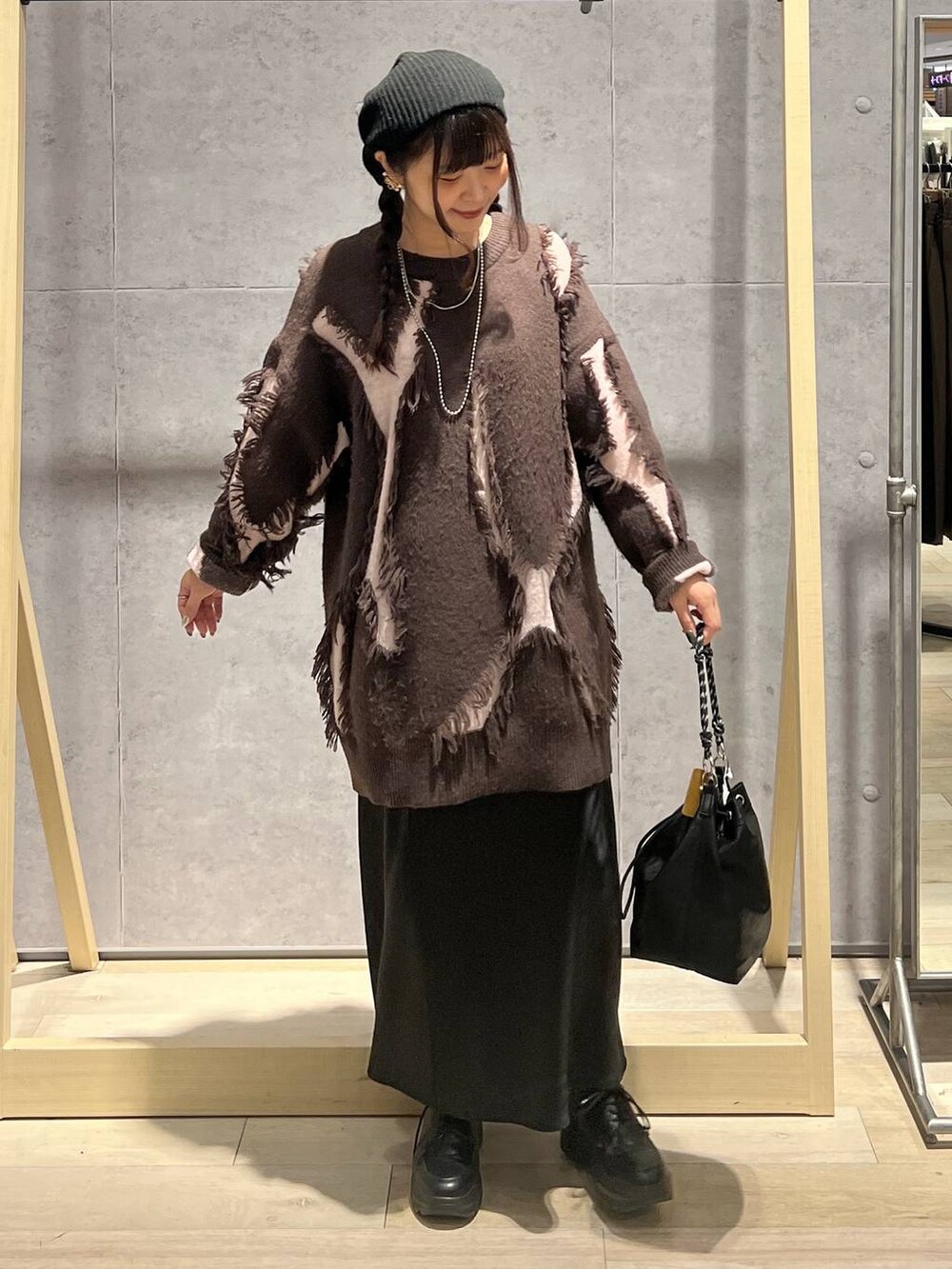 ブラック系のショルダーバッグ、ブラック系のスカート、ブラウン系のニット/セーターを着用したレディースの冬コーディネートの5枚目の写真