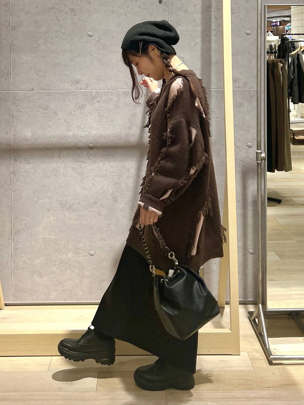 ブラック系のショルダーバッグ、ブラック系のスカート、ブラウン系のニット/セーターを着用したレディースの冬コーディネートの4枚目の写真