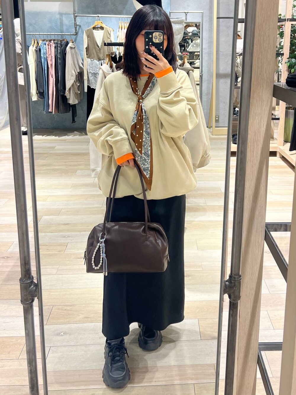 ブラック系のスカート、ブラウン系のボストンバッグ、ベージュ系のTシャツ/カットソーを着用したレディースの冬コーディネートの4枚目の写真