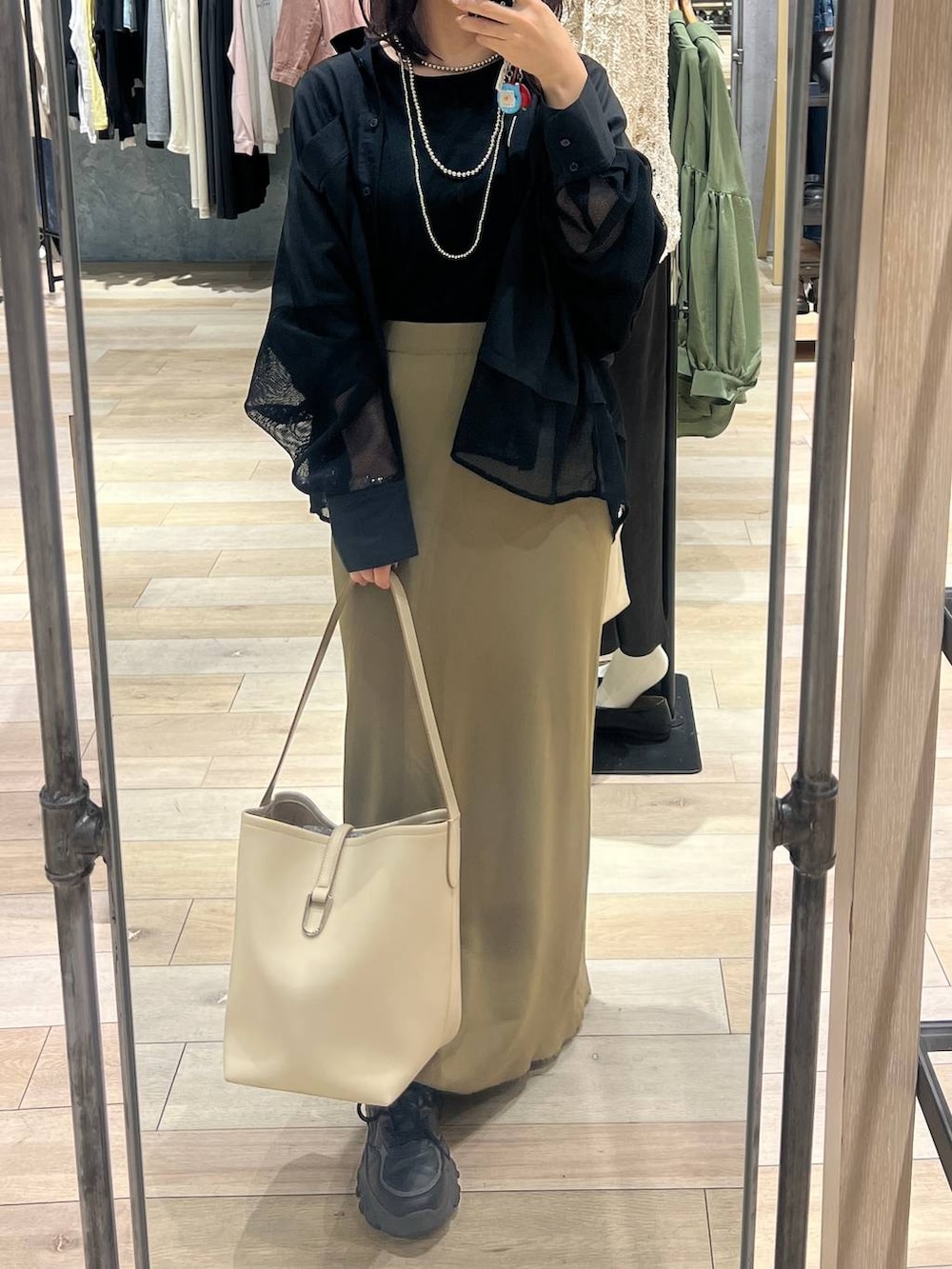 グリーン系のスカート、ホワイト系のトートバッグ、ブラック系のシャツ/ブラウスを着用したレディースの春コーディネートの4枚目の写真