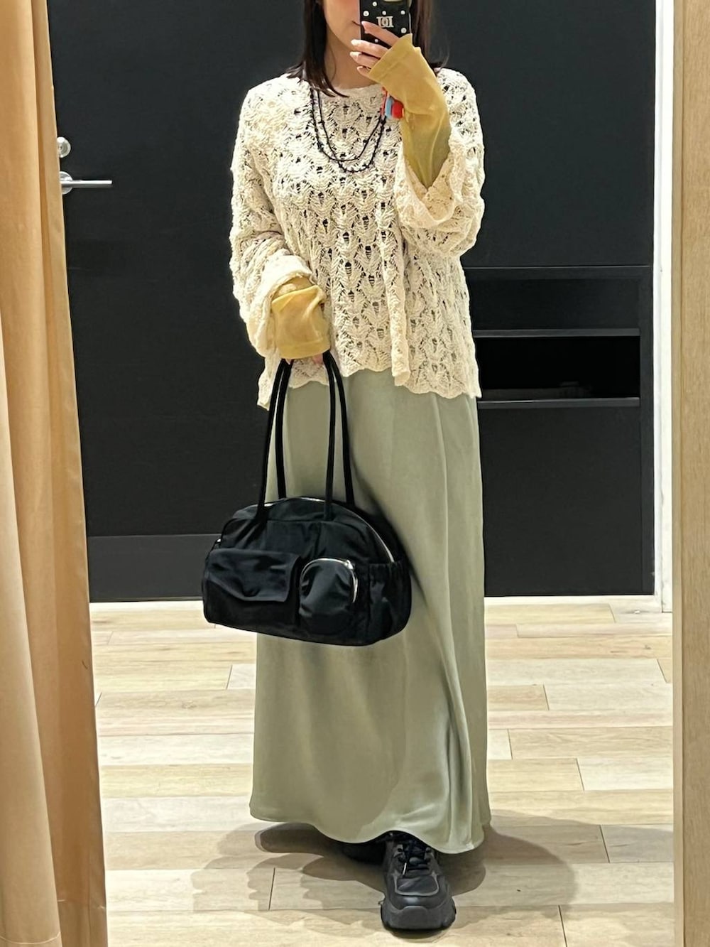 ブラック系のTシャツ/カットソー、ブラック系のボストンバッグ、ベージュ系のニット/セーターを着用したレディースの春コーディネートの3枚目の写真