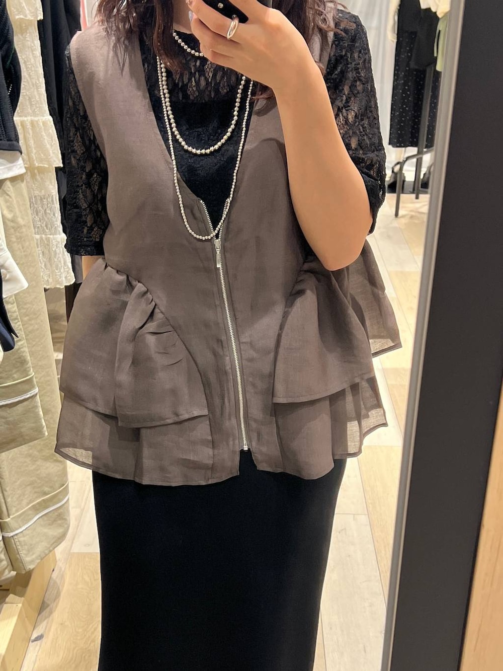 ブラック系のスカート、ブラウン系のベスト、ブラック系のTシャツ/カットソーを着用したレディースの春コーディネートの4枚目の写真