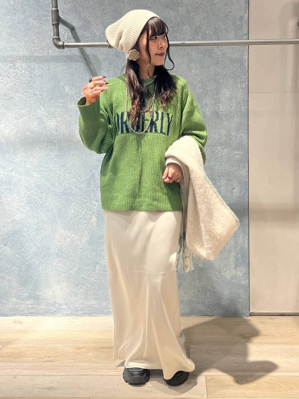 ブラック系のTシャツ/カットソー、ホワイト系のスカート、グリーン系のニット/セーターを着用したレディースの冬コーディネートの6枚目の写真