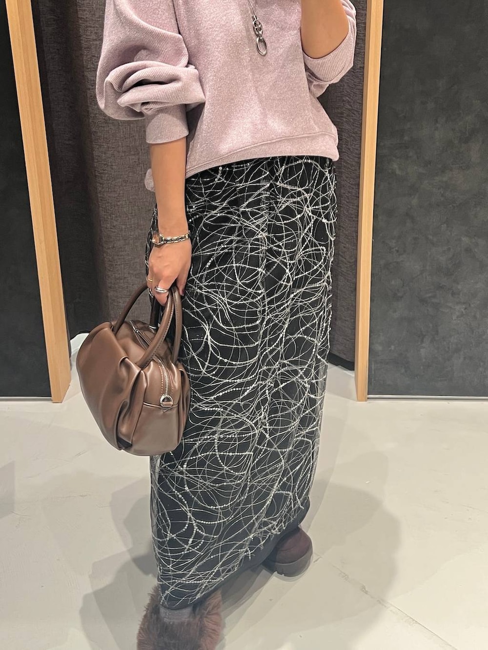ブラウン系のショルダーバッグ、ブラック系のスカート、パープル系のTシャツ/カットソーを着用したレディースの秋コーディネートの3枚目の写真