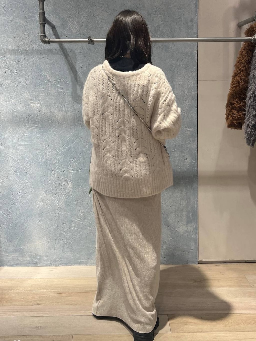 シルバー系のショルダーバッグ、ブラック系のニット/セーター、ホワイト系のスカートを着用したレディースの冬コーディネートの3枚目の写真