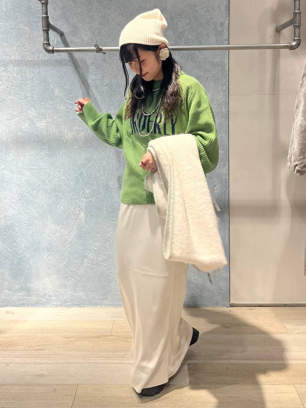 ブラック系のTシャツ/カットソー、ホワイト系のスカート、グリーン系のニット/セーターを着用したレディースの冬コーディネートの5枚目の写真