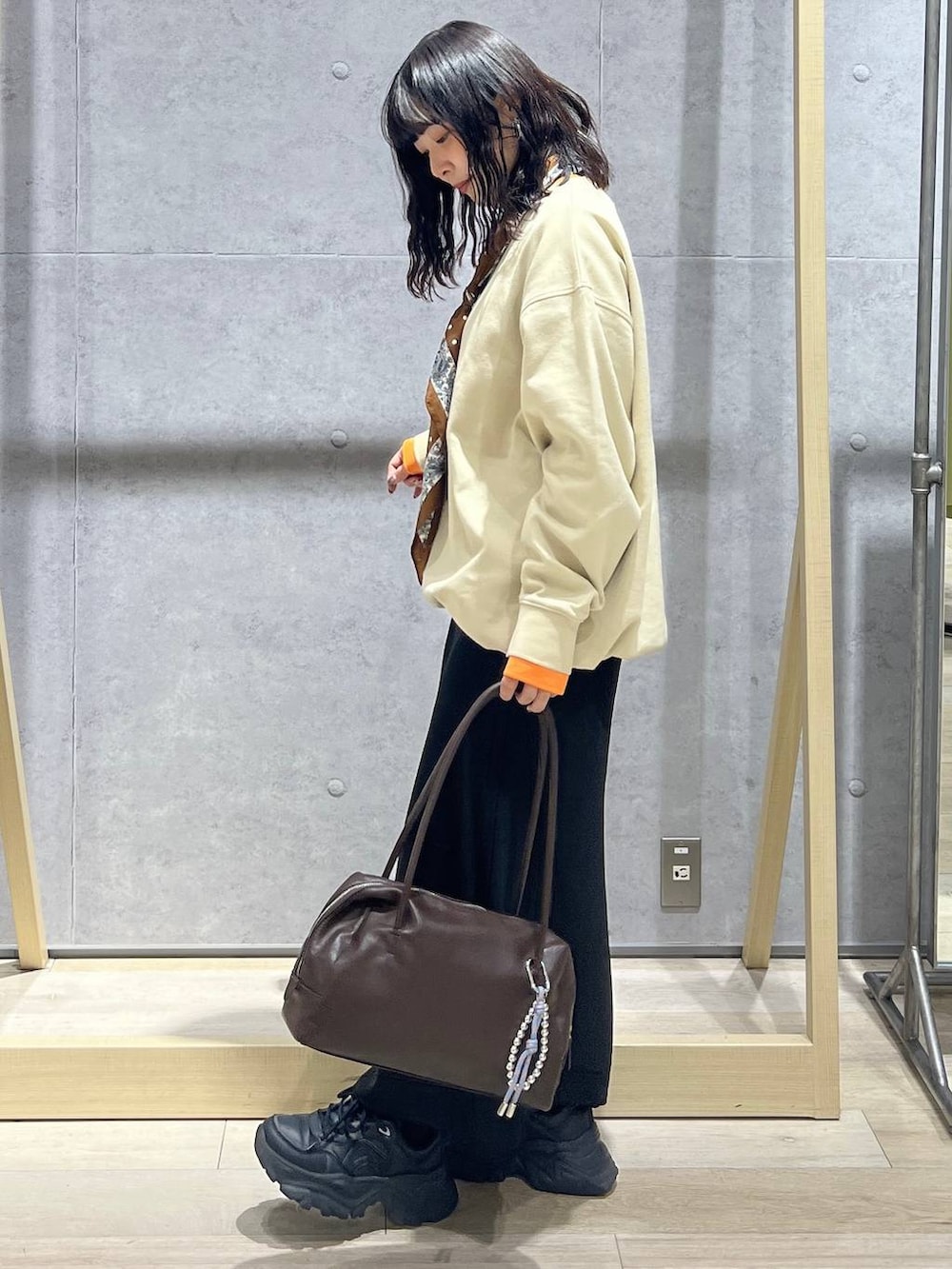 ブラック系のスカート、ブラウン系のボストンバッグ、ベージュ系のTシャツ/カットソーを着用したレディースの冬コーディネートの2枚目の写真