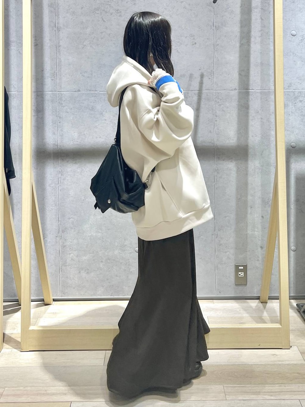 ホワイト系のパーカー、ブラック系のショルダーバッグ、ブラウン系のスカートを着用したレディースの春コーディネートの3枚目の写真