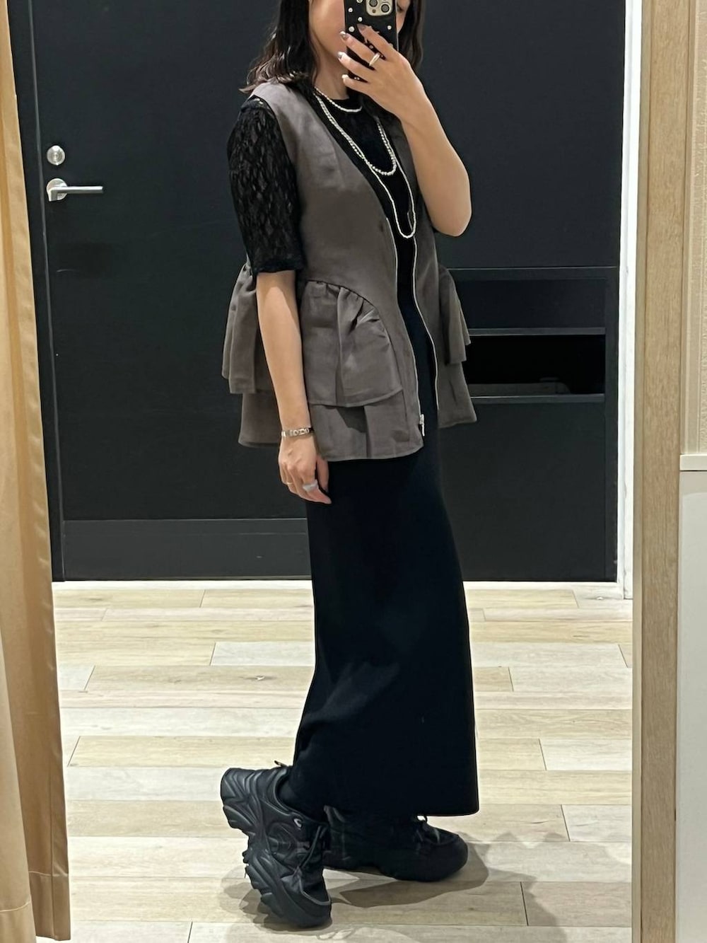 ブラック系のスカート、ブラウン系のベスト、ブラック系のTシャツ/カットソーを着用したレディースの春コーディネートの2枚目の写真