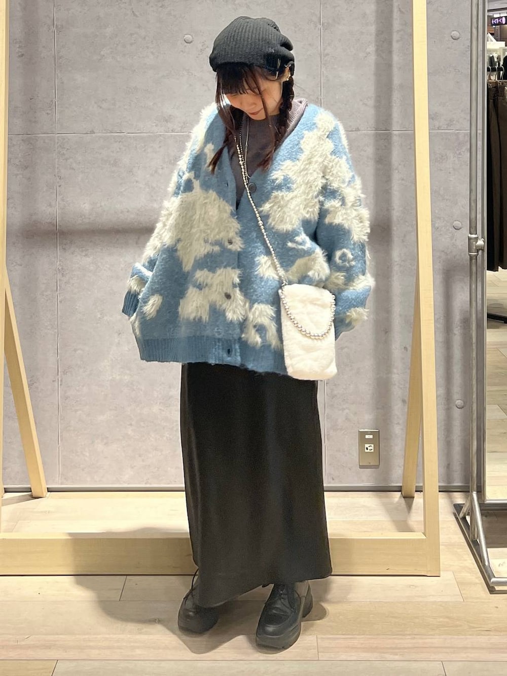 ブラック系のスカート、グレー系のニット/セーター、ホワイト系のショルダーバッグを着用したレディースの秋コーディネートの5枚目の写真