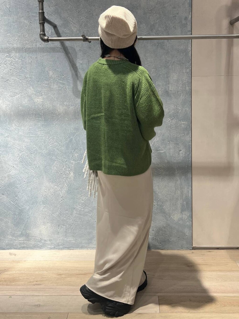 ブラック系のTシャツ/カットソー、ホワイト系のスカート、グリーン系のニット/セーターを着用したレディースの冬コーディネートの3枚目の写真