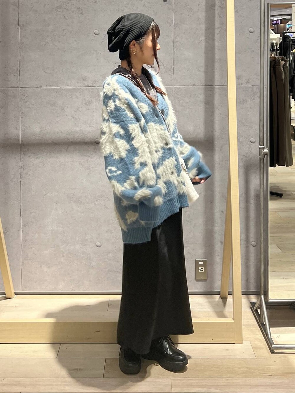 ブラック系のスカート、グレー系のニット/セーター、ホワイト系のショルダーバッグを着用したレディースの秋コーディネートの2枚目の写真