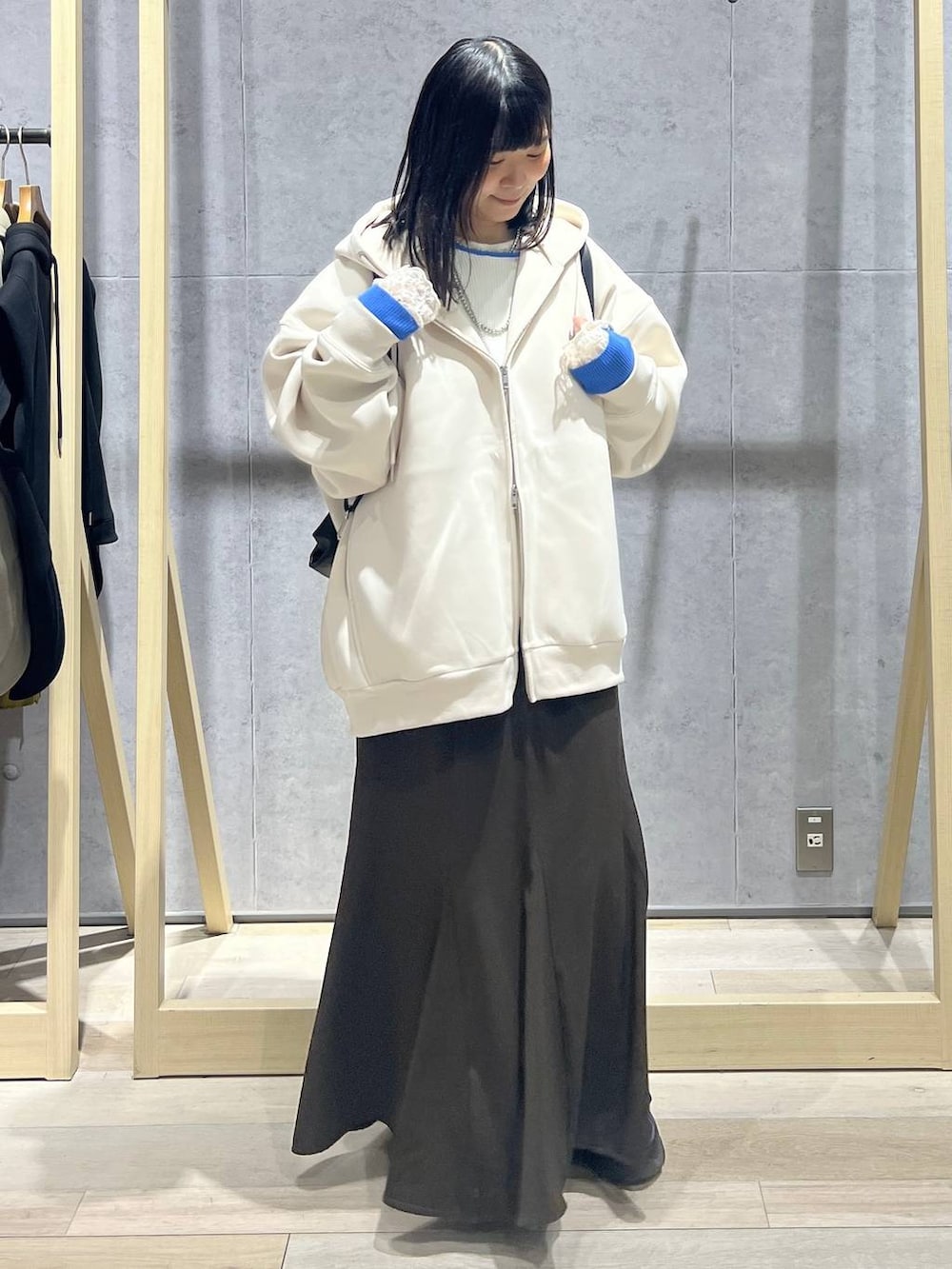 ホワイト系のパーカー、ブラック系のショルダーバッグ、ブラウン系のスカートを着用したレディースの春コーディネートの5枚目の写真