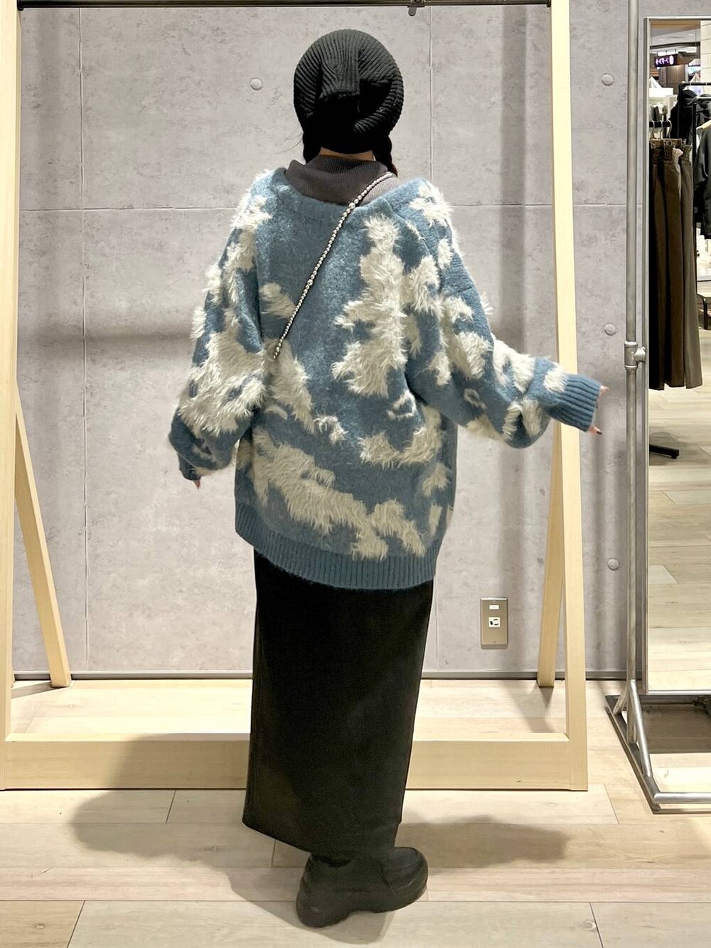 ブラック系のスカート、グレー系のニット/セーター、ホワイト系のショルダーバッグを着用したレディースの秋コーディネートの3枚目の写真