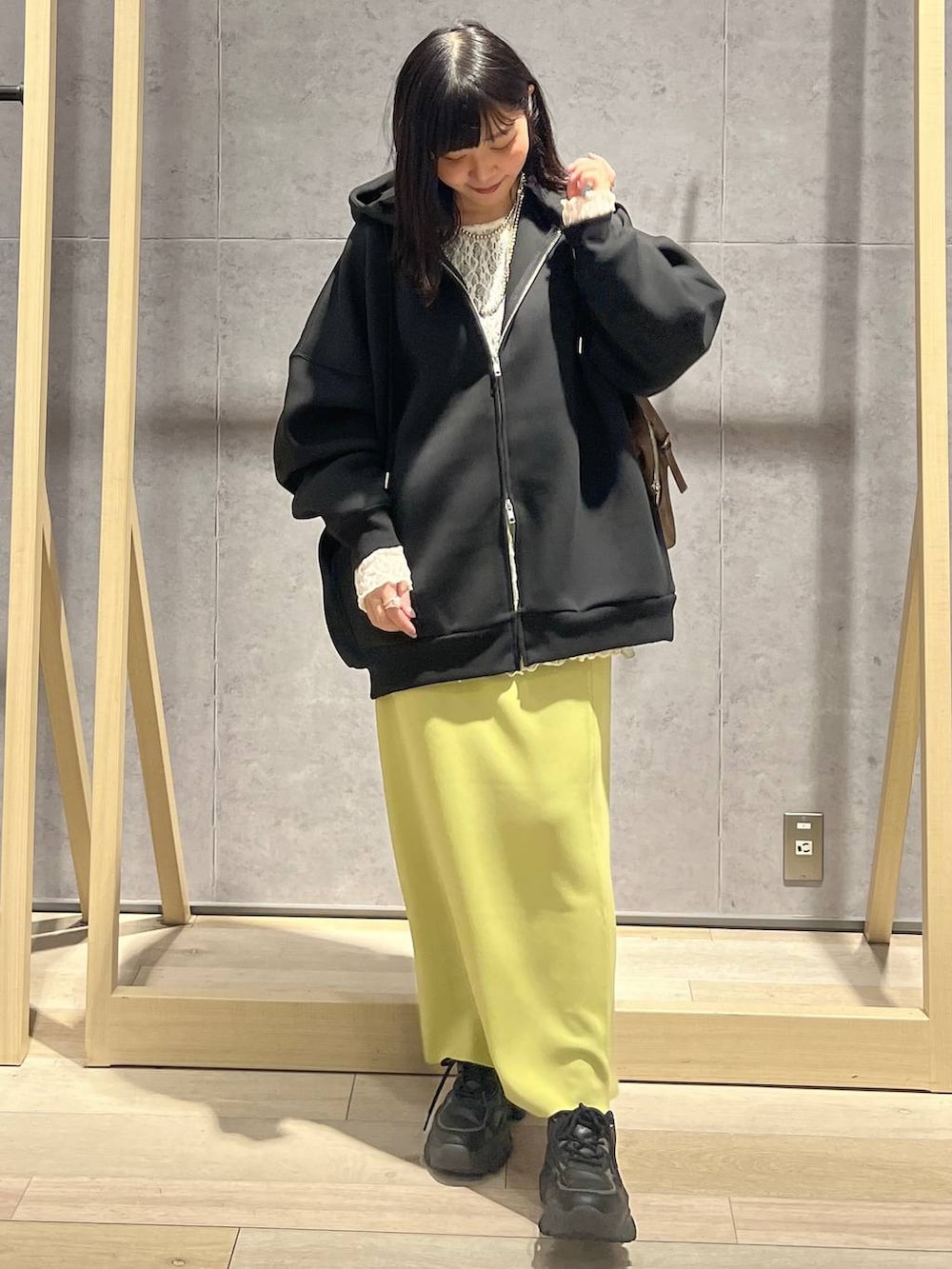 グリーン系のスカート、ブラック系のパーカー、ブラウン系のボストンバッグを着用したレディースの冬コーディネートの7枚目の写真