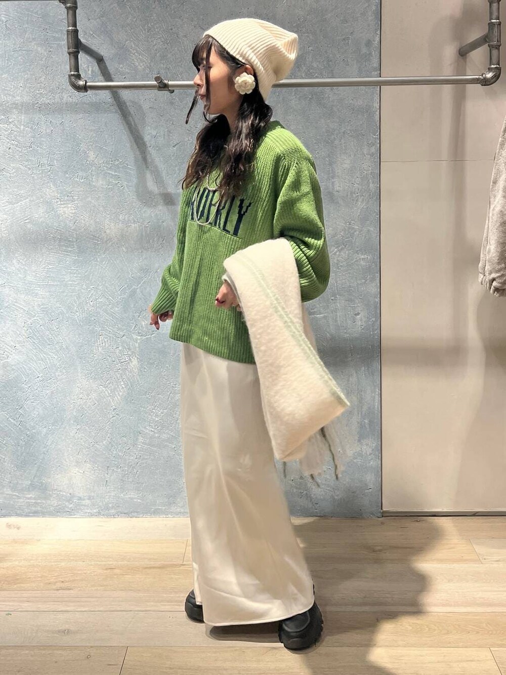 ブラック系のTシャツ/カットソー、ホワイト系のスカート、グリーン系のニット/セーターを着用したレディースの冬コーディネートの2枚目の写真