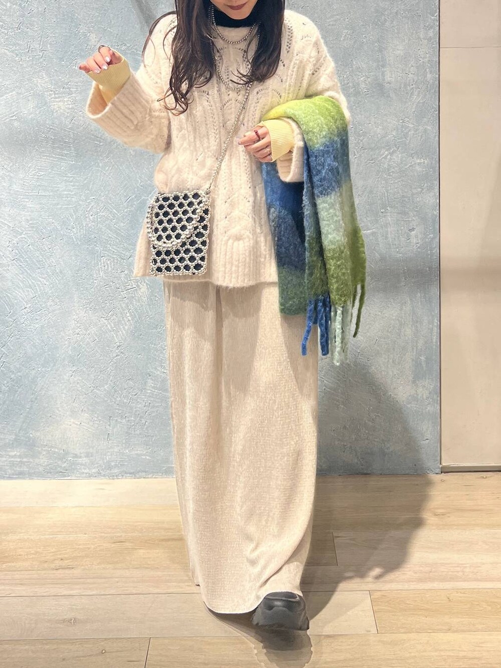 シルバー系のショルダーバッグ、ブラック系のニット/セーター、ホワイト系のスカートを着用したレディースの冬コーディネートの5枚目の写真