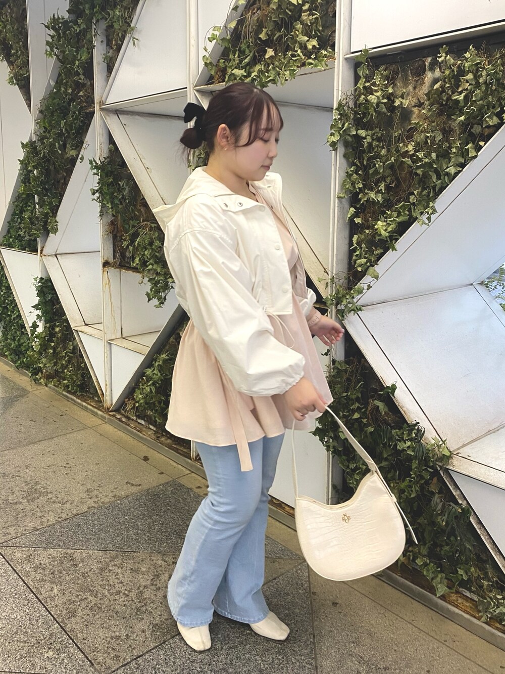 ピンク系のチュニック、ブルー系のデニムパンツ、ホワイト系のマウンテンパーカーを着用したレディースの春コーディネートの2枚目の写真