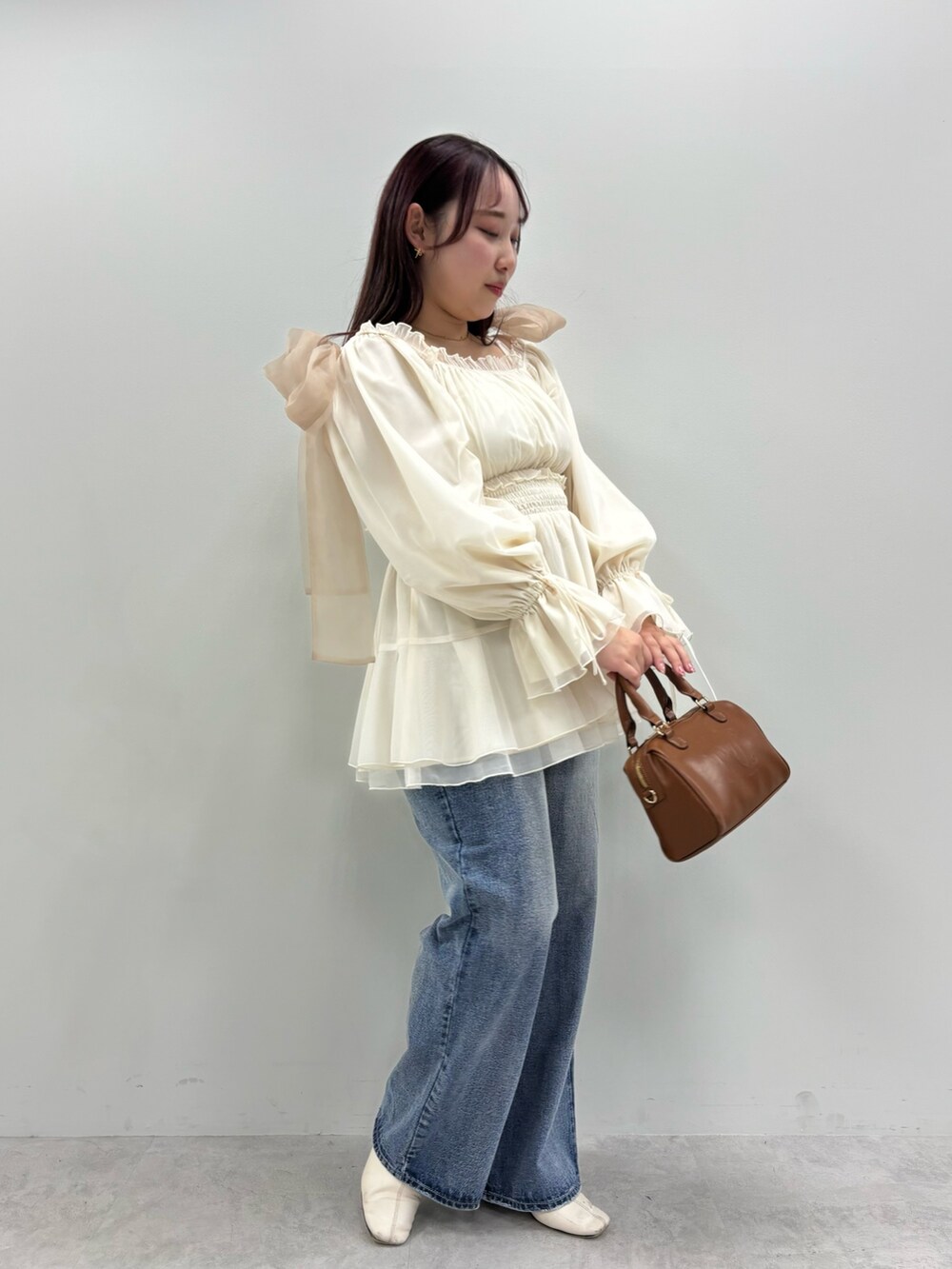 ブルー系のデニムパンツ、ホワイト系のシャツ/ブラウス、ブラウン系のボストンバッグを着用したレディースの春コーディネートの2枚目の写真