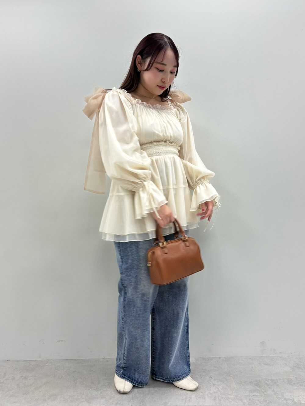 ブルー系のデニムパンツ、ホワイト系のシャツ/ブラウス、ブラウン系のボストンバッグを着用したレディースの春コーディネートの3枚目の写真