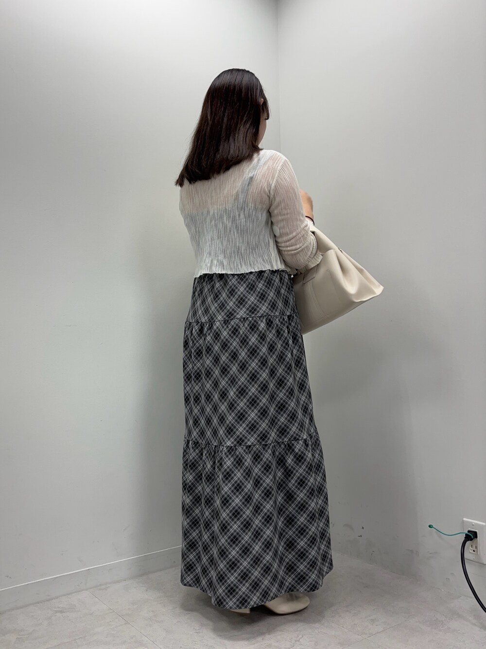 ブラック系のワンピース、ブラウン系のハンドバッグ、ホワイト系のカーディガン/ボレロを着用したレディースの夏コーディネートの2枚目の写真