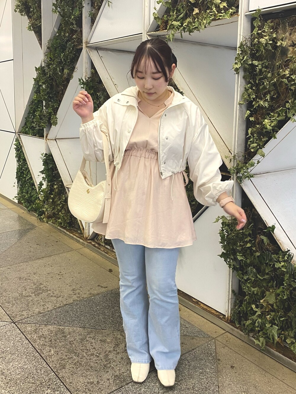 ピンク系のチュニック、ブルー系のデニムパンツ、ホワイト系のマウンテンパーカーを着用したレディースの春コーディネートの3枚目の写真