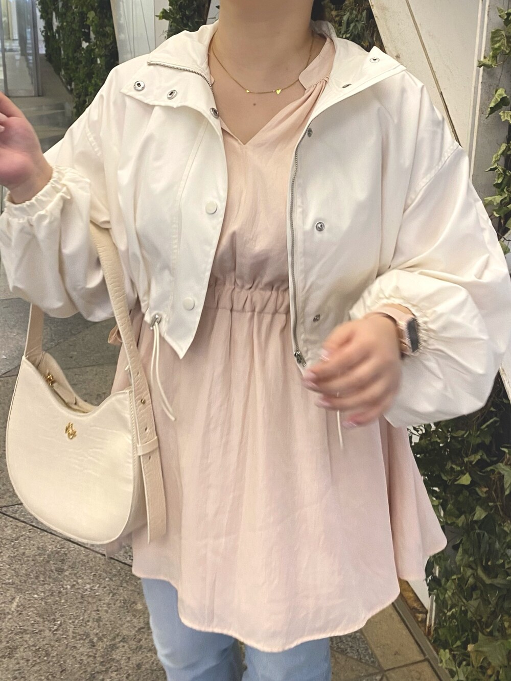 ピンク系のチュニック、ブルー系のデニムパンツ、ホワイト系のマウンテンパーカーを着用したレディースの春コーディネートの4枚目の写真