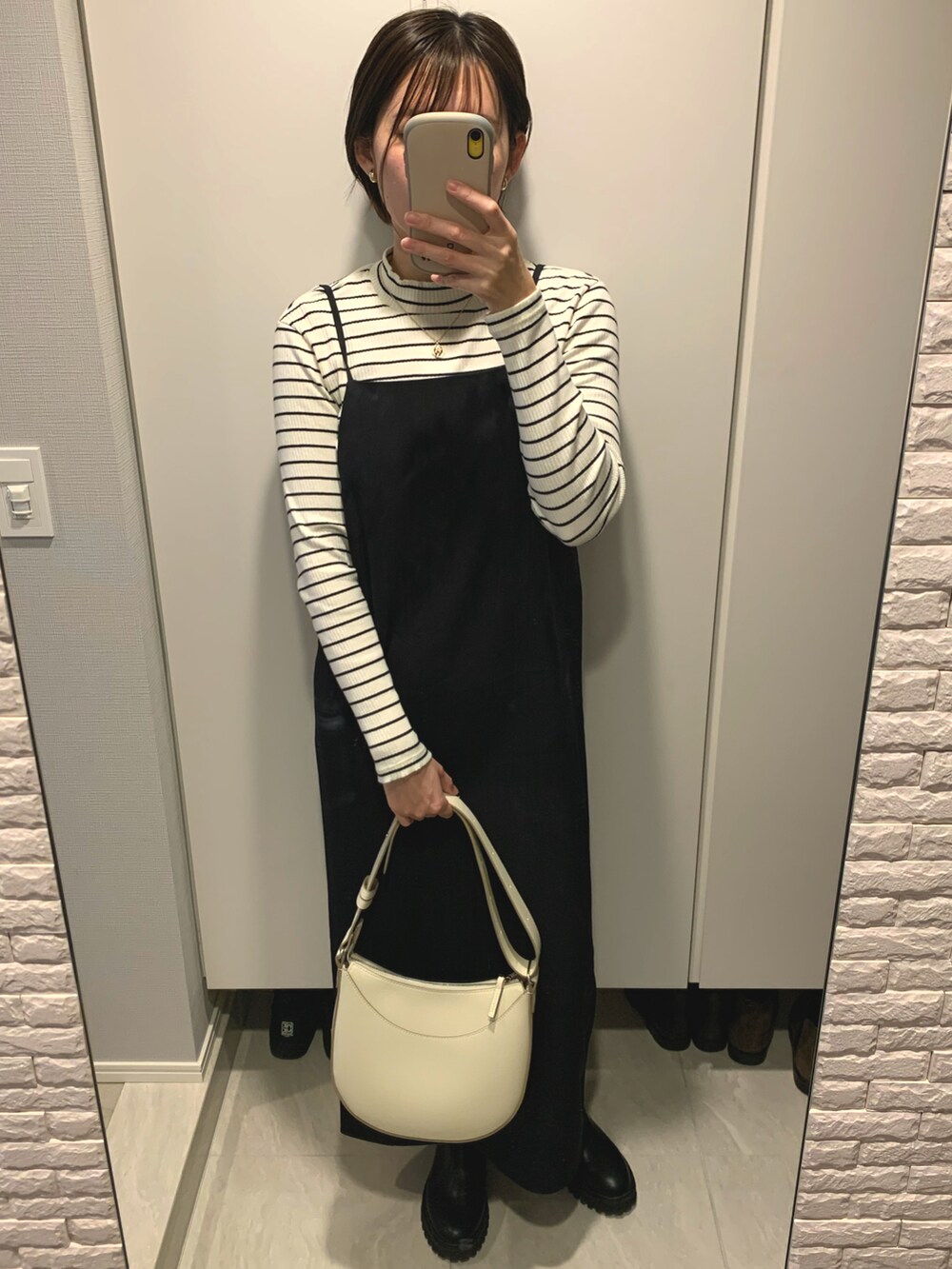 ブルー系のデニムジャケット、ブラック系のワンピース、ブラック系のブーツを着用したレディースの春コーディネートの3枚目の写真