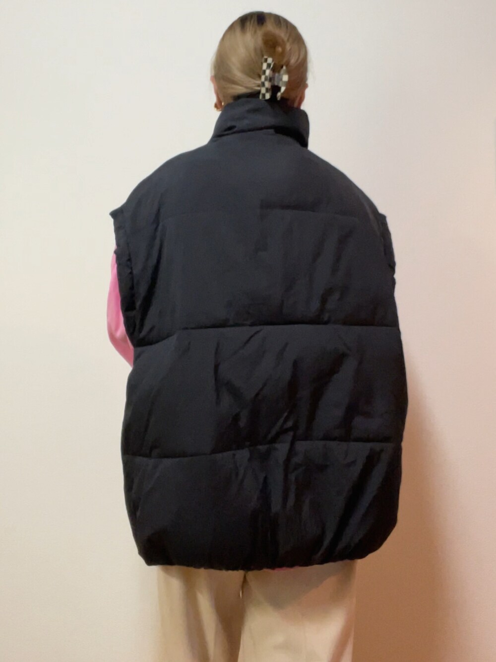 ブラック系のダウンベスト、ピンク系のスウェット、シルバー系のエコバッグ/サブバッグを着用したレディースの冬コーディネートの3枚目の写真