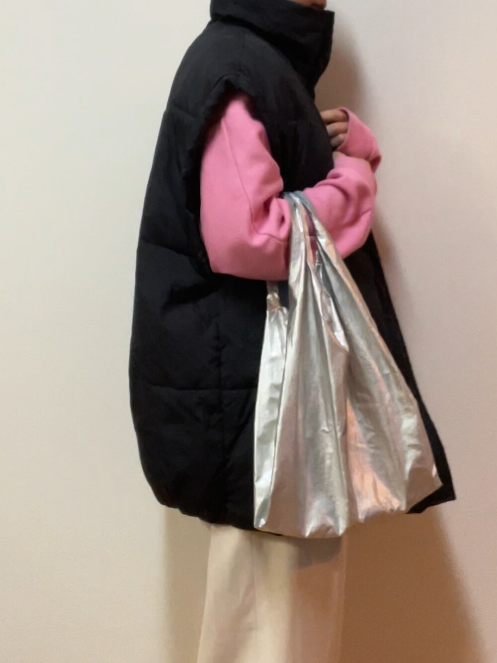 ブラック系のダウンベスト、ピンク系のスウェット、シルバー系のエコバッグ/サブバッグを着用したレディースの冬コーディネートの2枚目の写真