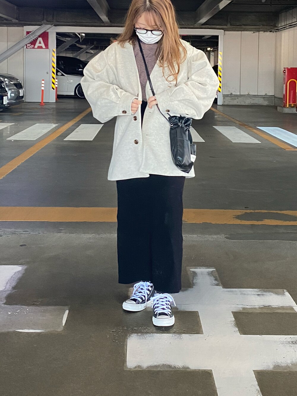 ベージュ系のノーカラーコート、ブラック系のショルダーバッグ、ブラック系のスカートを着用したレディースの冬コーディネートの2枚目の写真