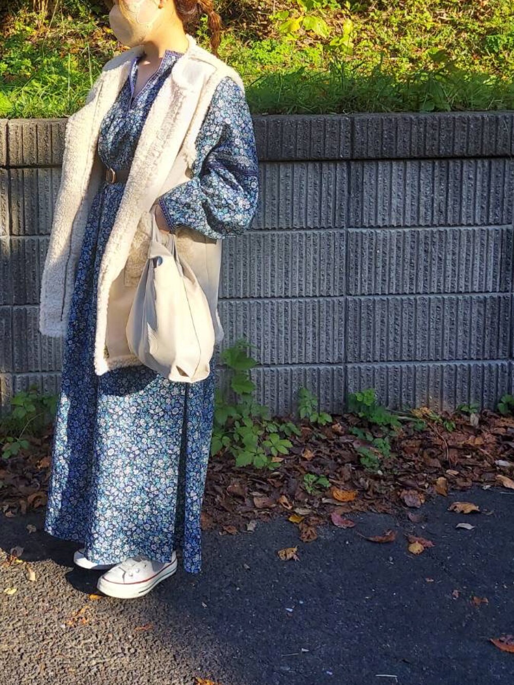 ホワイト系のベスト、グリーン系のワンピース、ホワイト系のバッグを着用したレディースの秋コーディネートの2枚目の写真