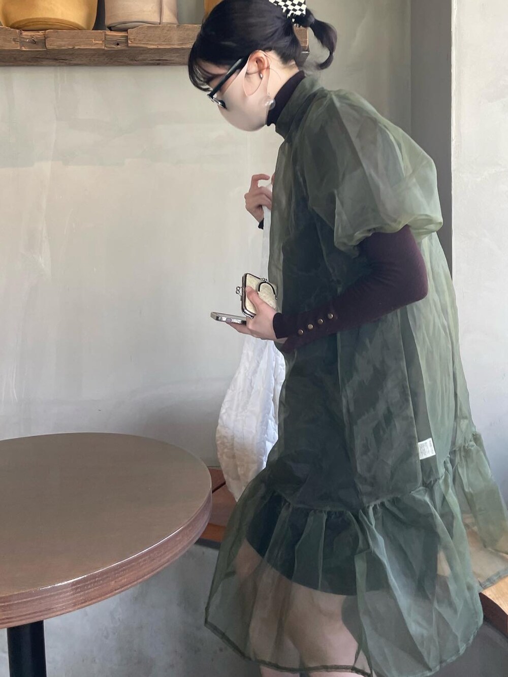 ブラック系のサンダル、グリーン系のワンピース、ブラウン系のニット/セーターを着用したレディースの春コーディネートの2枚目の写真