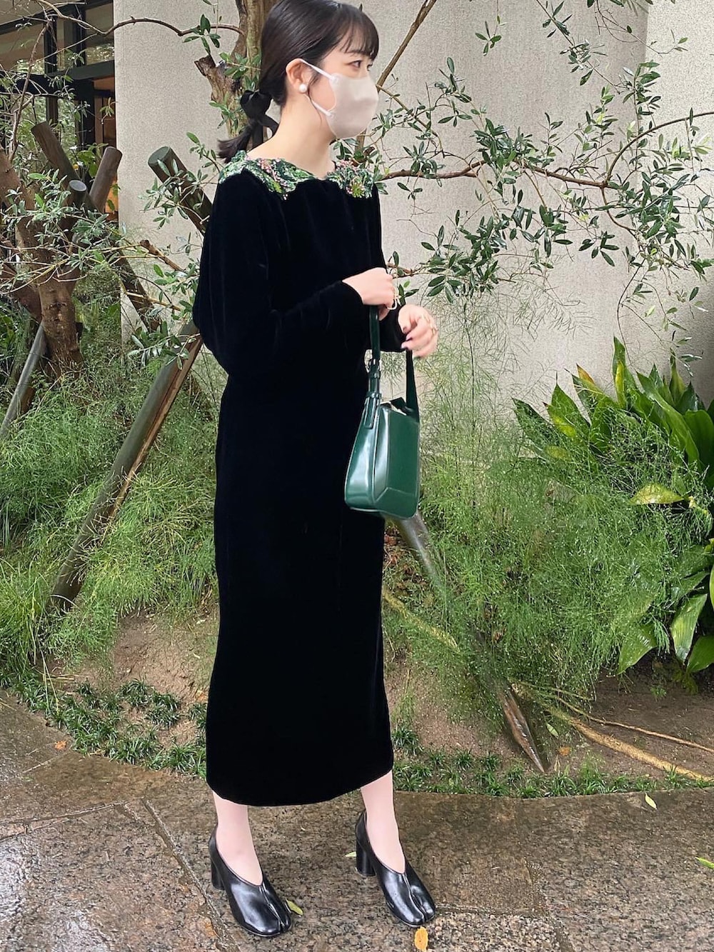 ブラック系のドレス、グリーン系のハンドバッグを着用したレディースの秋コーディネートの2枚目の写真