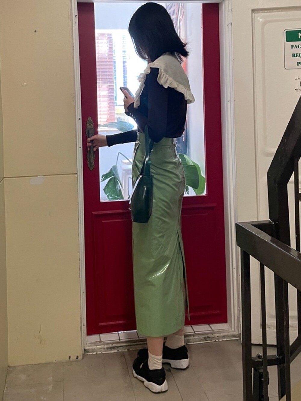 グリーン系のスカート、ブラウン系のニット/セーター、グリーン系のハンドバッグを着用したレディースの秋コーディネートの2枚目の写真