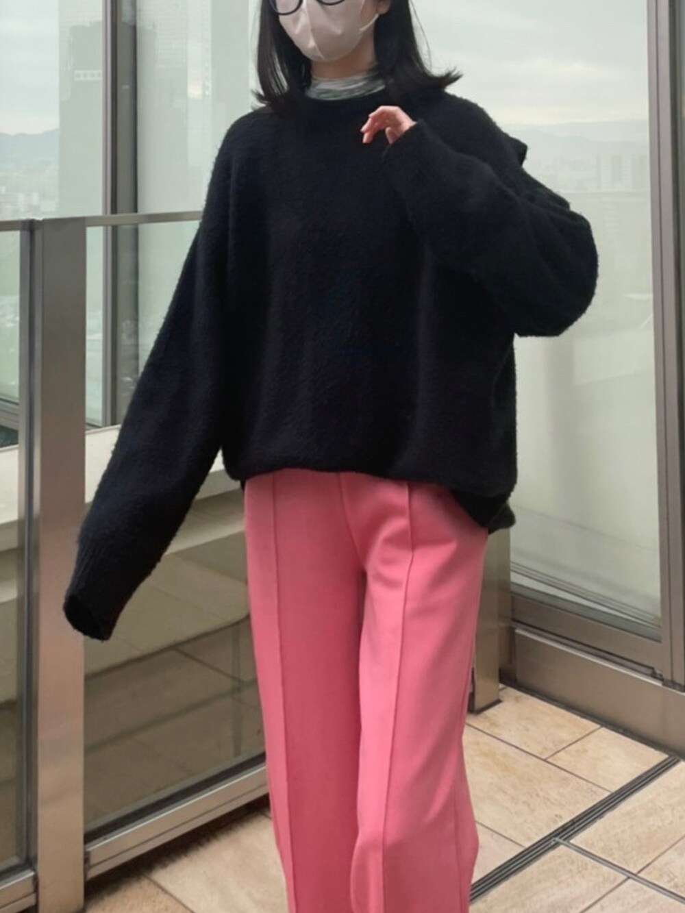 グリーン系のハンドバッグ、ブラック系のニット/セーター、ピンク系のスウェットパンツを着用したレディースの秋コーディネートの2枚目の写真