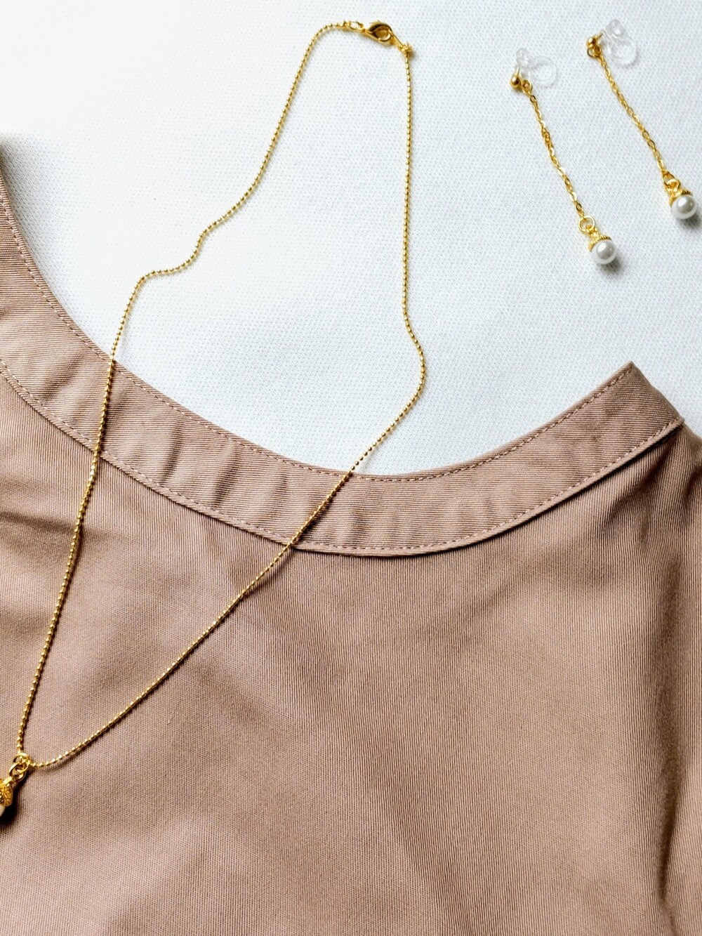 ベージュ系のワンピース、ブラウン系のショルダーバッグ、ゴールド系のネックレスを着用したレディースの秋コーディネートの2枚目の写真