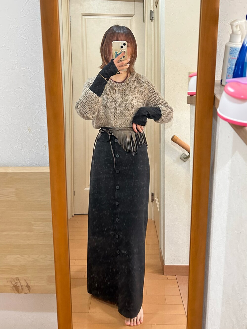 グレー系のニット/セーター、ブラック系のスカート、ホワイト系のベストを着用したレディースの冬コーディネートの2枚目の写真