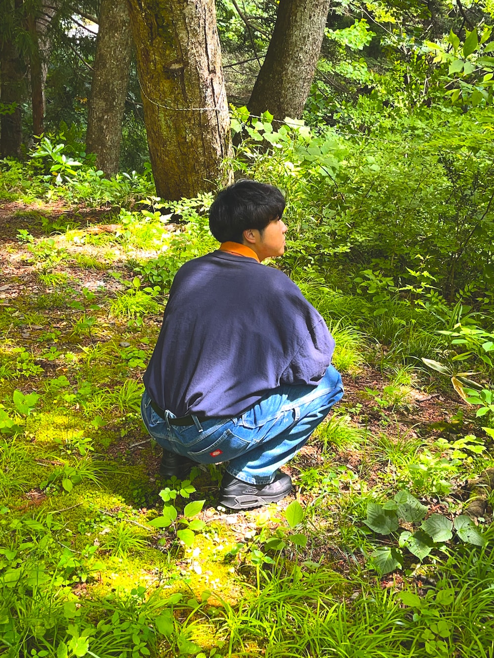 オレンジ系のトップス、ブルー系のポロシャツ、ブルー系のデニムパンツを着用したメンズの夏コーディネートの2枚目の写真