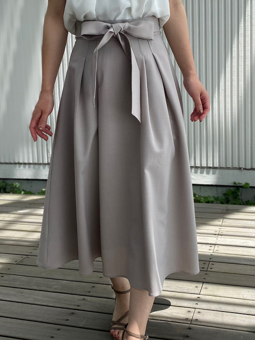 ベージュ系のサンダル、ベージュ系のハンドバッグ、ベージュ系のスカートを着用したレディースの夏コーディネートの4枚目の写真